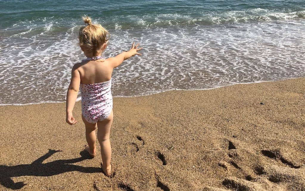 toddler walking towards waves Barcelona beach