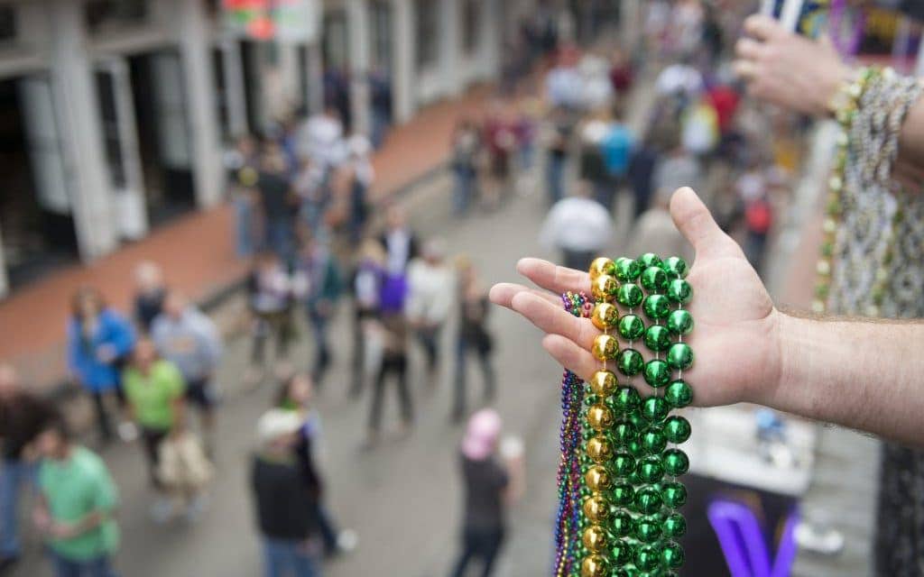 Mardi Gras beads in hand above Bourbon Street