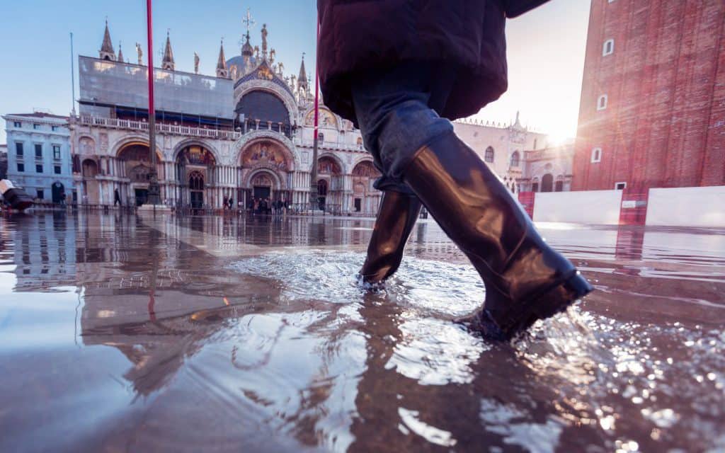 woman in rubber boots walking over St. Mark's Square in Venice