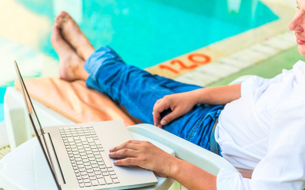 man working on his laptop by the pool