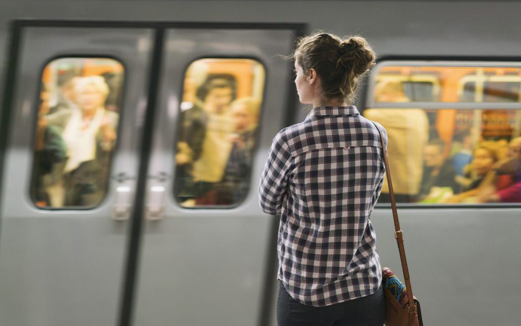 Young woman standing on the subway station and waiting for her train.