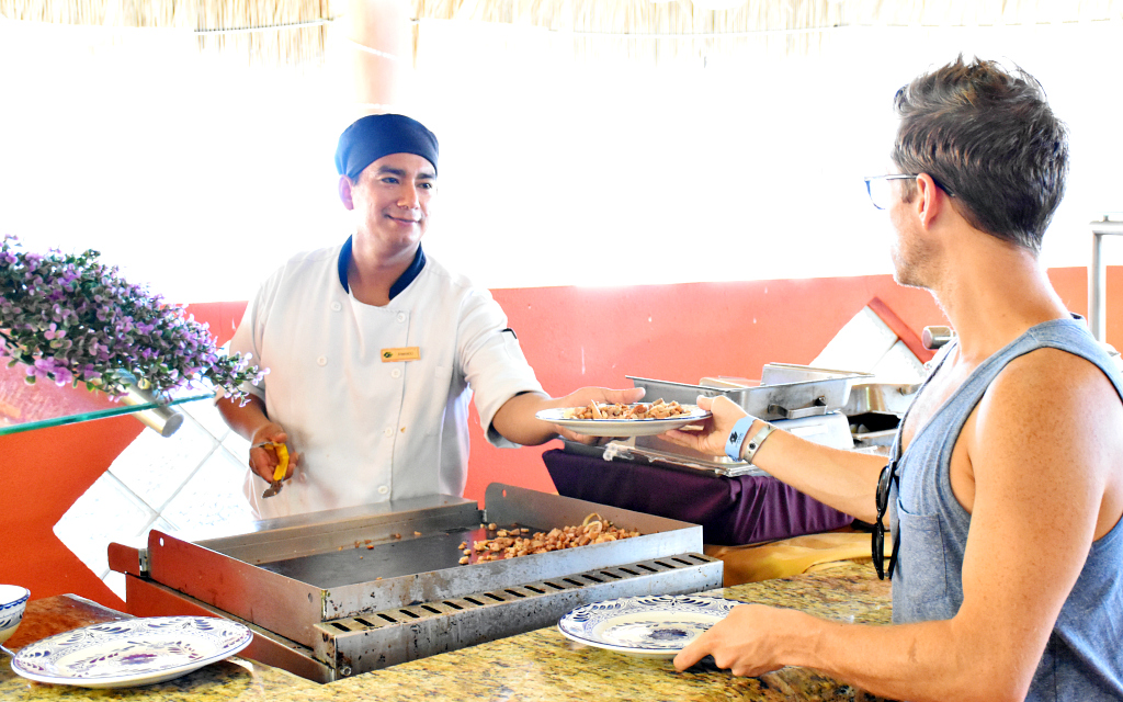 Chef in white jacket handing guest a plate of food