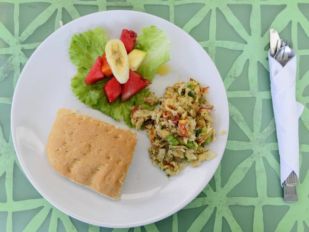 Salt fish and bake for breakfast in Tobago. Local caribbean dish served on a white plate and green table.