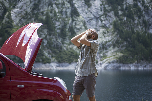 Car breakdown on mountain road. Frustrated young man despairing.