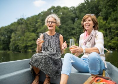 Cheerful women enjoying champagne on rowboat